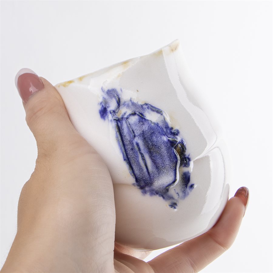 Petit verrre en porcelaine, contour oxydé et ornement bleu Petit verrre en porcelaine, contour oxydé et ornement bleu
